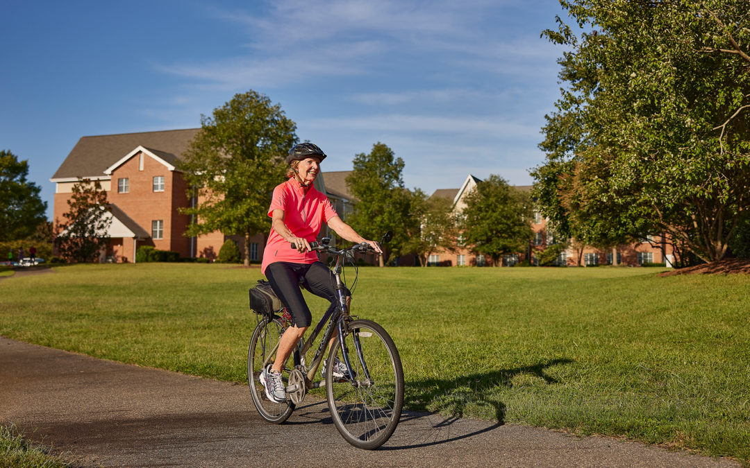 woman riding a bike down a paved trail surrounded by a large greenspace