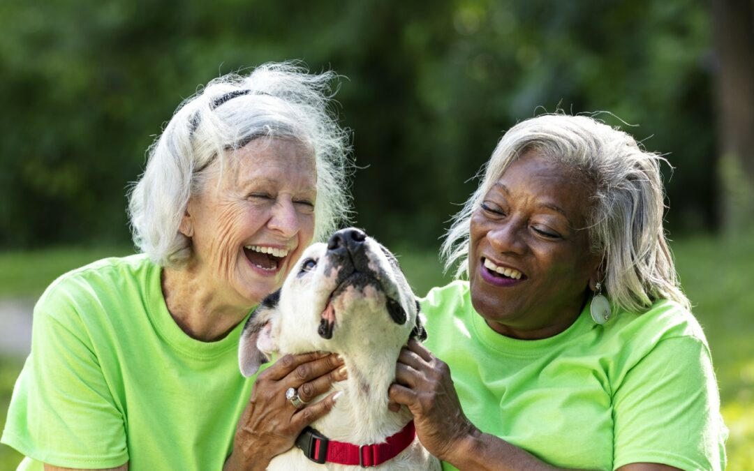 two senior women playing with a dog